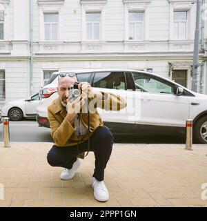 Un beau photographe de barbe prend des photos sur un appareil photo rétro Banque D'Images