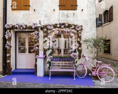 Venzone, Italie - 29 décembre 2022: Magasin de lavande dans la ville médiévale de Venzone, Friuli, et un vélo rose décoratif Banque D'Images