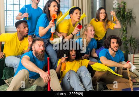 Fans de football supporter des amis applaudissent et regardant le match de coupe de football à la maison Intenational - Groupe de jeunes avec des t-shirts multicolores ayant le plaisir wi Banque D'Images