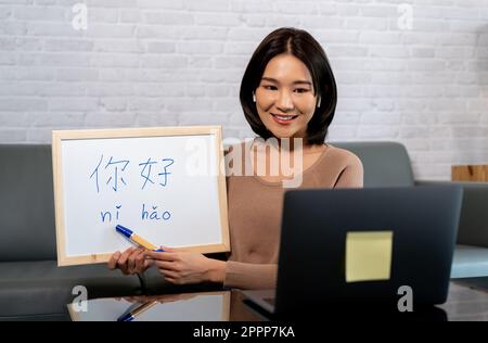 Jeune enseignante asiatique enseignant d'une langue chinoise via l'enseignement à distance en ligne sur ordinateur portable à la maison. Cours de langue de tutorat de langue maternelle chinoise sur Internet. Ni Hao signifie bonjour en anglais Banque D'Images