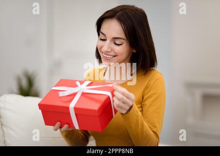 Gros plan d'une belle jeune femme tenant une boîte cadeau rouge Banque D'Images