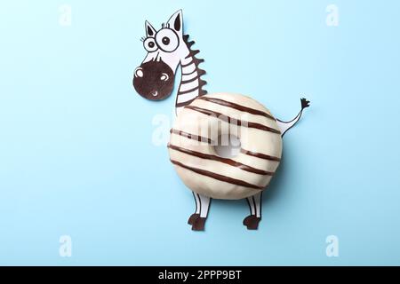 Zèbre drôle fait avec donut sur fond bleu clair, vue de dessus Banque D'Images