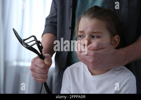 Homme avec ceinture couvrant la bouche de petite fille effrayée à l'intérieur. Violence domestique Banque D'Images