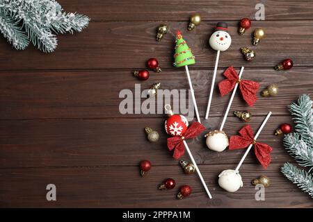 Délicieux gâteau de Noël avec branches de sapin et boules sur table en bois, plat. Espace pour le texte Banque D'Images