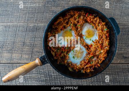 Ragoût de chou avec des légumes et des œufs frits dans une poêle sur fond de bois, gros plan, vue de dessus. La nourriture. Une alimentation saine Banque D'Images