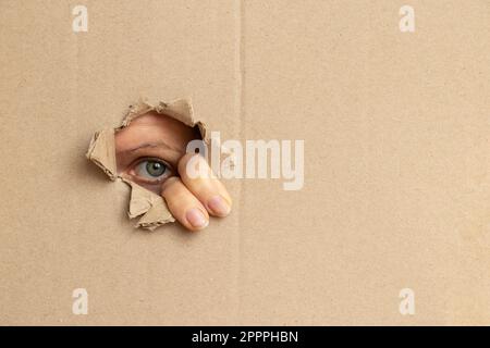 L'œil de la fille regarde dans le trou de carton, regardez Banque D'Images