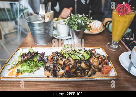 Sélection de l'accent sur un sandwich avec des champignons, avocat, laitue et graines servi avec des boissons sur une table en bois restaurant Banque D'Images