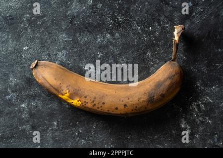 Banane surmûre brune sur fond noir. Gros plan, vue de dessus Banque D'Images