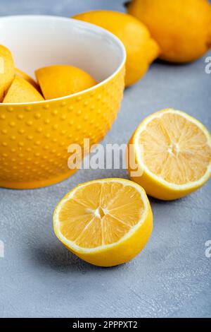 Citrons dans un bol; entiers et coupés en deux. Gros plan. Banque D'Images