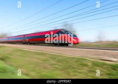 Train de voyageurs à grande vitesse rouge moderne lors d'une journée de printemps claire. Effet de flou de mouvement. Banque D'Images