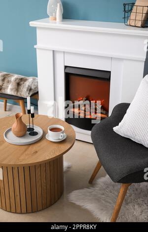 Table basse avec tasse de thé, verseuse et bougies dans le salon Banque D'Images