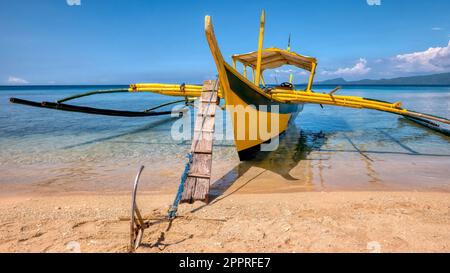 Vue rapprochée de l'arc d'un bateau à stabilisateur en bois aux Philippines, connu localement sous le nom de banca, ancré dans des eaux turquoise peu profondes. Banque D'Images