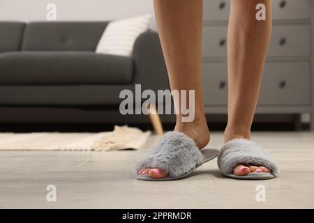 Femme portant des chaussons gris doux à la maison, gros plan Banque D'Images