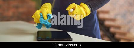 Dose de produit nettoyant en gants de caoutchouc et uniforme à l'aide d'un spray désinfectant antibactérien et d'un chiffon en microfibre tout en désinfectant le Banque D'Images