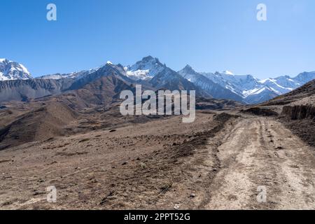 Une route de terre dans la vallée de Mustang au Népal avec les pics de neige qui montent en arrière-plan. Banque D'Images