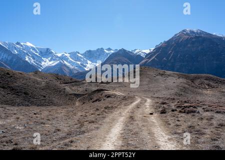 Une route de terre dans la vallée de Mustang au Népal avec les pics de neige qui montent en arrière-plan. Banque D'Images