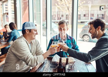 Se réunir avec mes meilleurs amis. trois amis masculins prenant un verre dans un bar. Banque D'Images