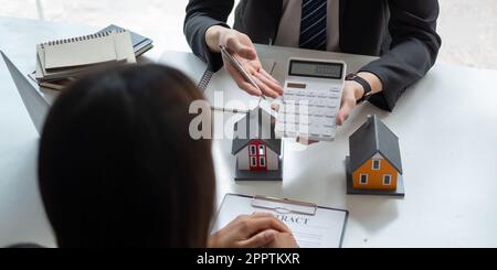 Les agents immobiliers parlent au client et offrent de bons taux d'intérêt et calculent les clients sur le financement hypothécaire pour les aider à décider des idées immobilières Banque D'Images