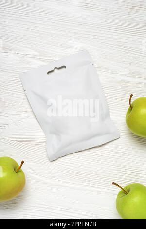 Sachet en plastique blanc avec pommes sur table en bois. Modèle de maquette pour la conception. Banque D'Images