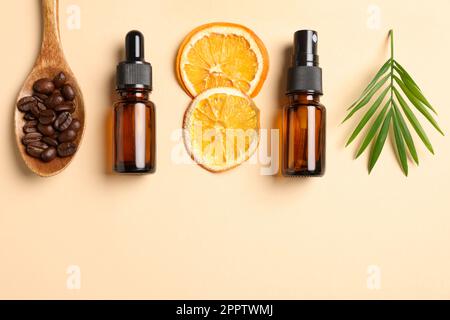 Bouteilles de produits cosmétiques biologiques, grains de café, tranches d'orange séchées et feuilles vertes sur fond beige, plat. Espace pour le texte Banque D'Images