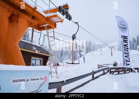 Iogach, Russie - 10 mars 2018 : station de ski d'hiver Teletsky Altai. Ascenseur à fermoir sur le mont et le fond de la forêt sous les chutes de neige. L'inscription Banque D'Images