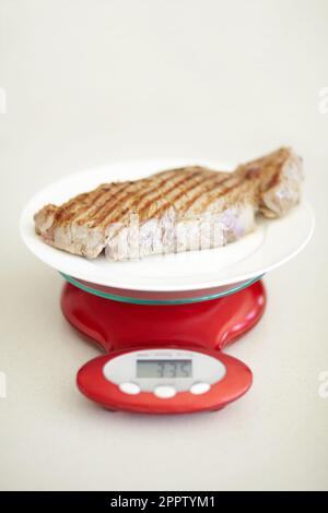 Pesée du dîner, balance et mesure du bœuf pour les calories, la valeur nutritive et les protéines sur une assiette. Viande saine, mesure et un steak pour l'alimentation Banque D'Images