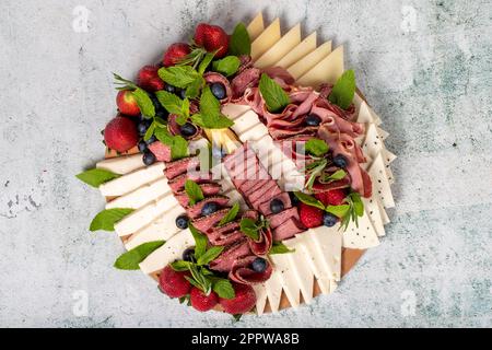 Plaque de jeu antipasti. Assiette de viande fumée froide. Antipasti au jambon, prosciutto, salami, fromage bleu, mozzarella aux myrtilles et fraises. Haut vi Banque D'Images