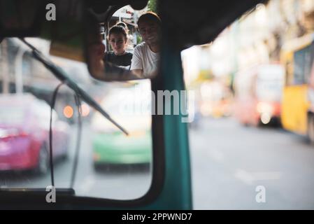 Reflet de deux touristes voyageant dans un tuk tuk taxi, Bangkok, Thaïlande Banque D'Images