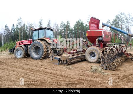 Un tracteur équipé d'une unité de semis connectée, une moissonneuse-batteuse, un semoir à roues larges permet de charrues le champ, de semer le grain, d'effectuer des travaux agricoles contre le bac Banque D'Images