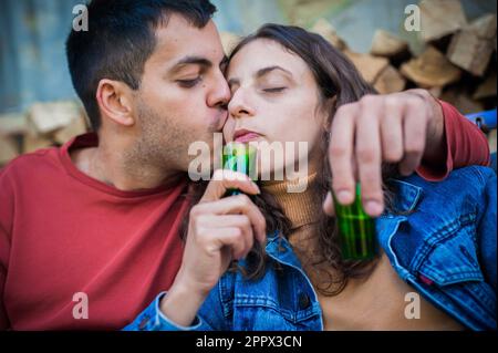 Un couple très ivre embrassant en amour embrassant et appréciant. Buvez une boisson alcoolisée forte dans de petits verres Banque D'Images