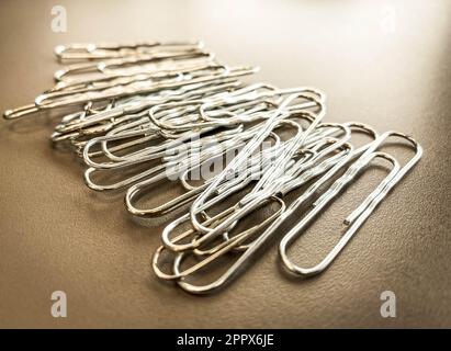 trombones en métal blanc pour conserver les documents ensemble de manière normale. articles de papeterie pour travailler avec des documents au bureau. Banque D'Images