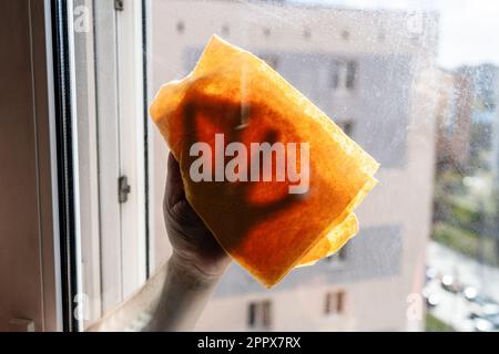 essuie-mains de homme sale côté extérieur de verre de fenêtre avec un chiffon dans la maison de ville de plusieurs étages l'après-midi ensoleillé de printemps Banque D'Images