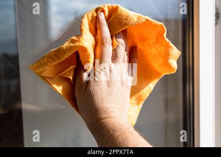 essuie-mains pour homme de la surface du verre de fenêtre avec un chiffon dans la maison urbaine le jour ensoleillé de près Banque D'Images