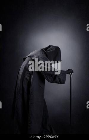 Personnage créepy dans un manteau à capuche avec le personnel sur fond sombre et brumeux Banque D'Images