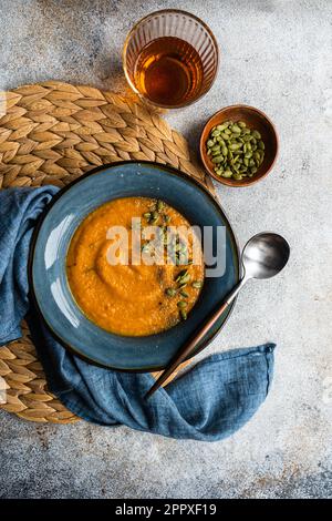 Savoureuse soupe à la crème de potiron aux herbes et aux graines biologiques dans un bol en céramique bleu vintage Banque D'Images