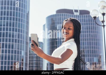 Bonne femme afro-américaine vêque de vêtements décontractés en autoportrait sur smartphone Banque D'Images