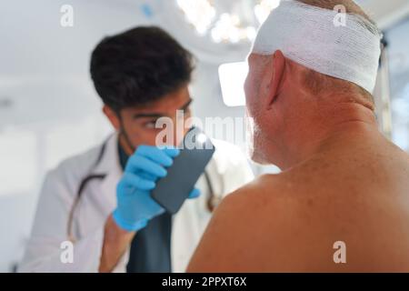 Médecin examinant l'homme âgé après un accident grave. Banque D'Images
