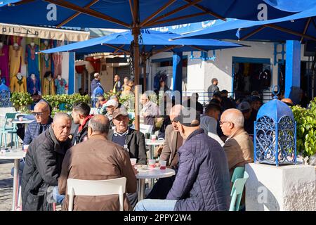 Sousse, Tunisie, 8 janvier 2023 : les hommes tunisiens âgés s'assoient sous des parasols dans le café et apprécient le matin avec du thé ou du café Banque D'Images