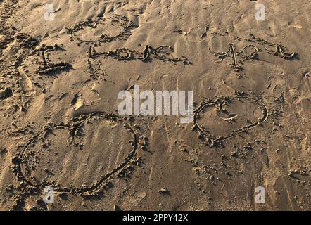 Charmante scène de plage: Je vous aime avec trois cœurs écrits dans le sable, vacances romantiques, Saint Valentin, mariage, relations, amoureux famille Banque D'Images