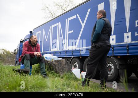 Weiterstadt, Allemagne. 25th avril 2023. Lors d'une grève des chauffeurs routiers d'une société de logistique polonaise à l'arrêt de repos Gräfenhausen West, deux chauffeurs s'assoient devant un camion qui indique « pas d'argent !!! » (Ing. « No Money ») y est écrit. Les chauffeurs de camions sont en grève depuis plus d'un mois pour les salaires impayés de leur employeur. Credit: Sebastian Christoph Gollnow/dpa/Alay Live News Banque D'Images