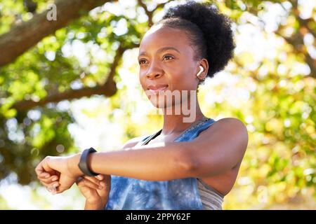 Portrait d'une jeune femme noire qui a l'air sérieuse, en vérifiant la montre de fitness avant la course Banque D'Images