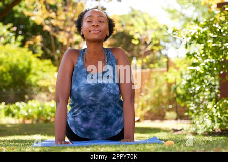 Belle jeune Black Woman fait face vers le haut chien yoga pose à l'extérieur, arbres Banque D'Images