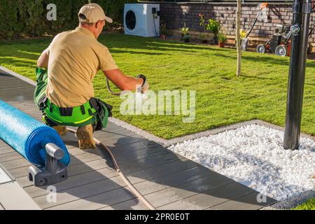 Homme caucasien arroser des tourfs d'herbe fraîche récemment installés à l'intérieur d'un jardin à l'aide d'un tuyau d'arrosage. Banque D'Images