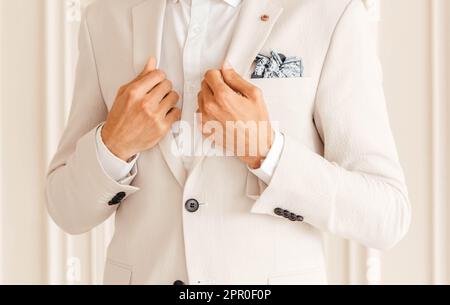 Mains du marié dans une veste blanche sur fond blanc. Banque D'Images