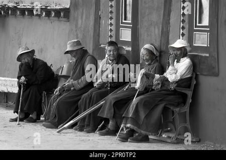 Les pratiquants bouddhistes sont assis sur un banc au monastère de Tagong (Lhagong) - Kham (Tibet oriental), province du Sichuan, Chine Banque D'Images