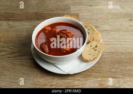 Soupe traditionnelle hongroise de Goulash avec du pain sur une table en bois Banque D'Images