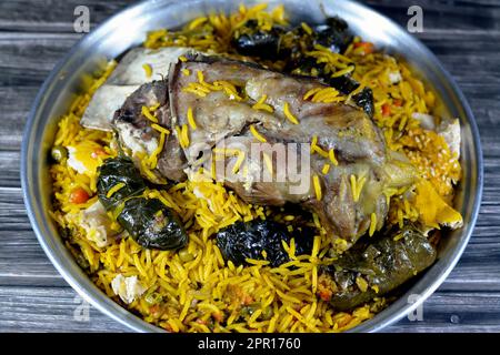 Une jarret d'agneau bien cuit avec du riz Basmati jaune et des légumes mélangés et des feuilles de raisin farcies mahshi Mahshy avec du riz blanc cuit rôti dans la ov Banque D'Images