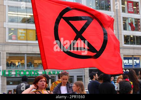 Une personne détient un drapeau rouge de la rébellion d'extinction dans le parc Union Square, à New York, au 21 avril 2023. Banque D'Images