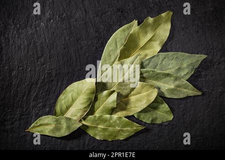 Un bouquet de feuilles de baie séchées sur fond noir. Épices aromatiques Laurier. Ingrédients de la recette. Banque D'Images