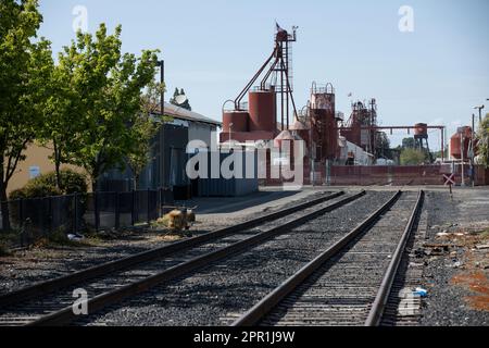 Oakdale, Californie, États-Unis - 18 avril 2023 : la lumière du soleil de l'après-midi brille sur les bâtiments industriels et les voies ferrées dans le centre-ville d'Oakdale. Banque D'Images